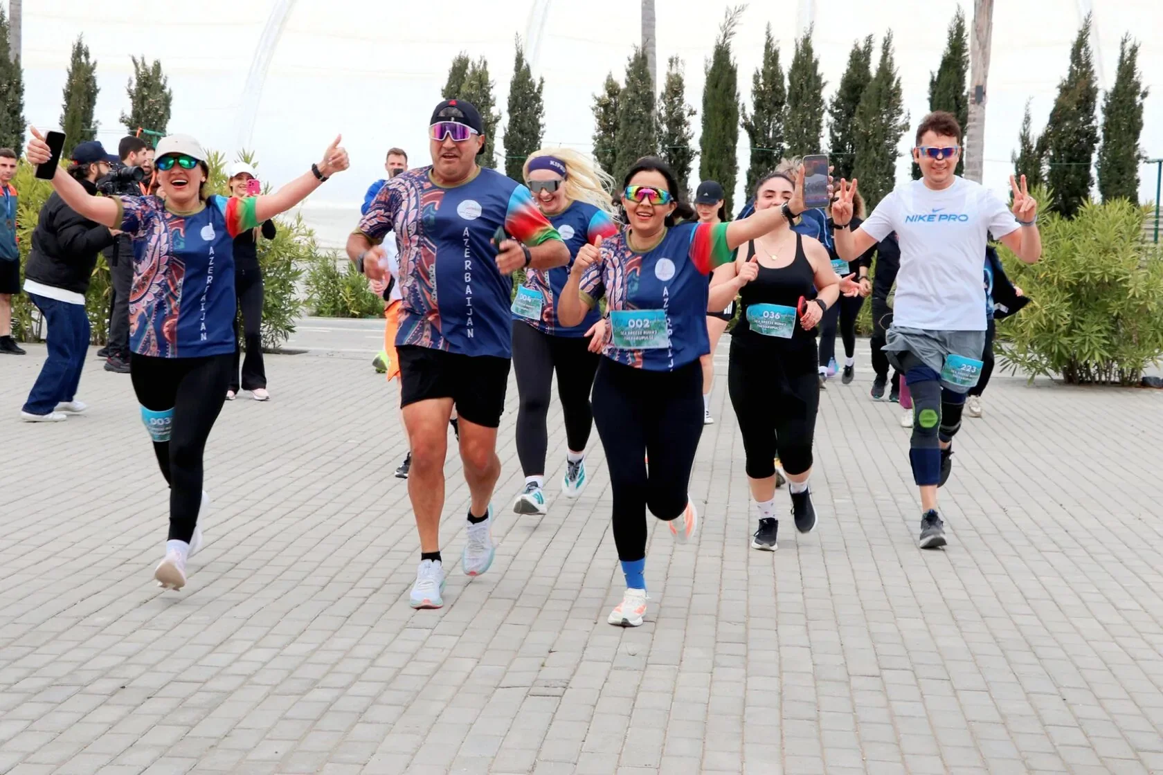 Бегуны Sea Breeze Run #2 на плиточной дорожке курорта, среди кипарисов